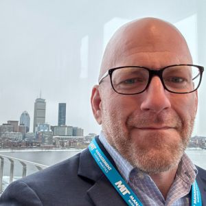 chris-myers-founder-cto Portrait of Chris Myers, Founder & CTO, wearing glasses and suit with a city skyline in the background